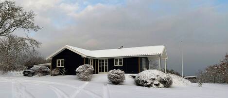 A house with a snow-covered roof, a garage, and a driveway.