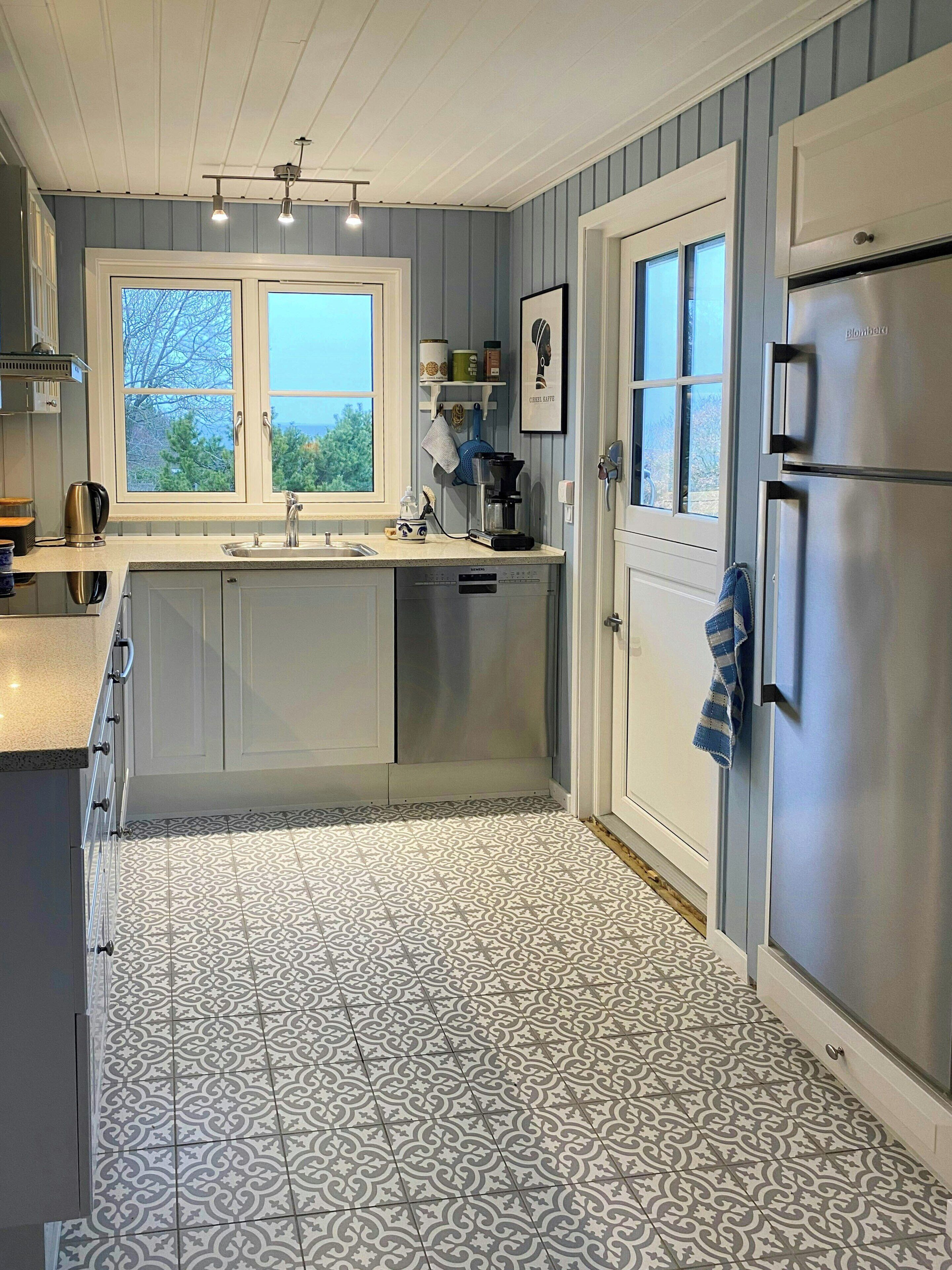 A kitchen with a window, a refrigerator, and a sink.