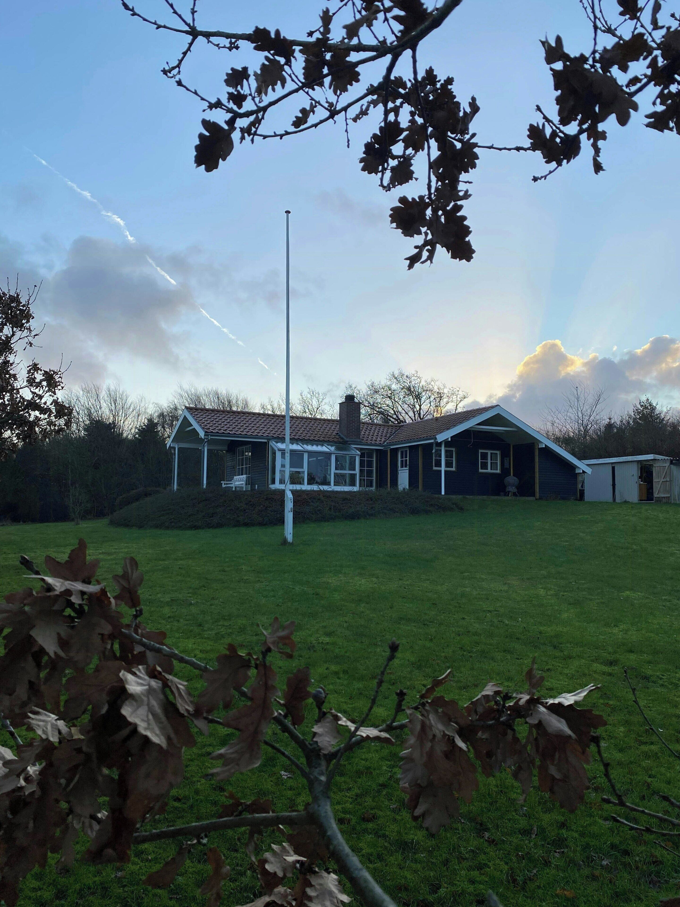 Een grasveld met een gebouw, een wimpel en een schoorsteen.