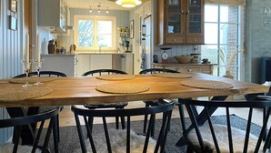 Een eethoek met een houten tafel, zwarte stoelen en geweven onderzetters.