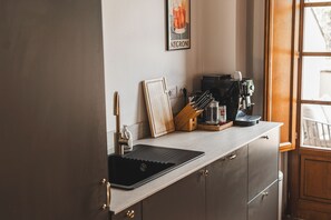 A kitchen with a sink, a coffee machine, and a framed picture on the counter. - Borgo di Gaiole – Stylish Tuscan Retreat with Pool in the Heart of Chiant (Gaiole in Chianti)