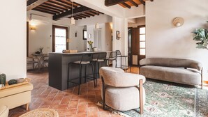 Un salón amplio con un sofá, una silla, una cocina con barra y una mesa de comedor.