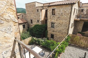 A stone building with a courtyard, a wooden fence, and a table with chairs. - Borgo di Gaiole – Stylish Tuscan Retreat with Pool in the Heart of Chiant (Gaiole in Chianti)