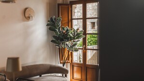 Una habitación con puerta de madera, planta en maceta, sofá marrón y una mesa de comedor con sillas.