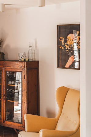 A room with a wooden cabinet, a framed picture, and a yellow armchair. - Borgo di Gaiole – Stylish Tuscan Retreat with Pool in the Heart of Chiant (Gaiole in Chianti)