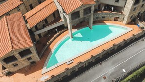 Un patio con piscina rodeado de edificios de piedra y techos de teja.