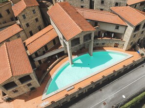 Ein Innenhof mit Schwimmbad, umgeben von Steinhäusern mit Terrakottadächern.