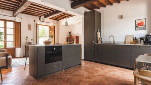 Una cocina con armarios oscuros, suelo de baldosas y techo de madera.