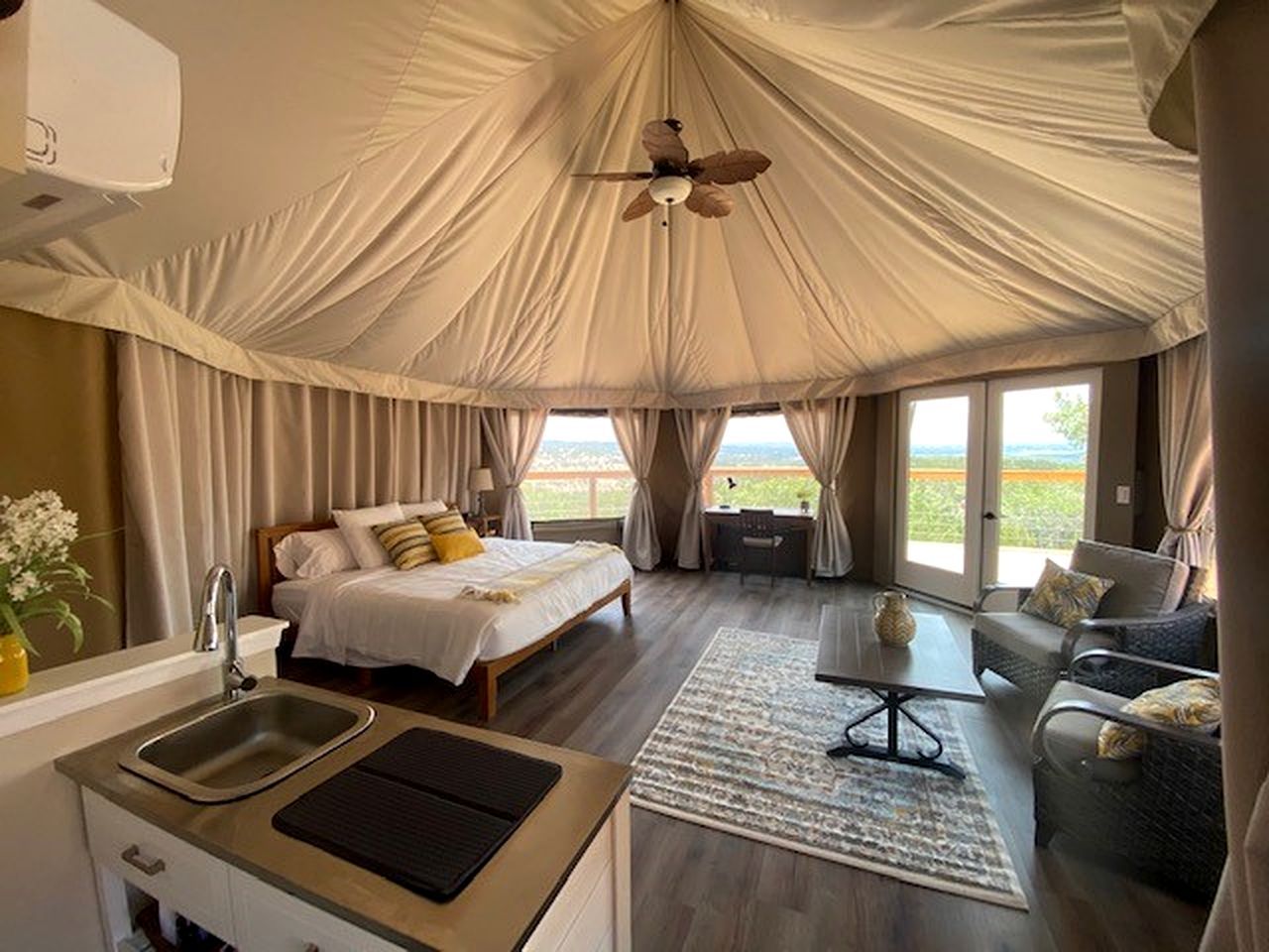 Una habitación tipo tienda de campaña con cama, escritorio, silla y vistas al exterior.