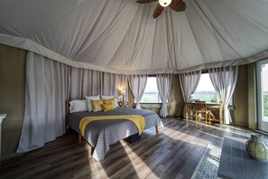 A tent-style bedroom with a bed, curtains, a table, and a chair.