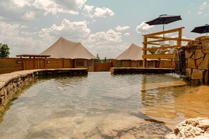 Ett spaområde med en pool, ett trädäck och tält.