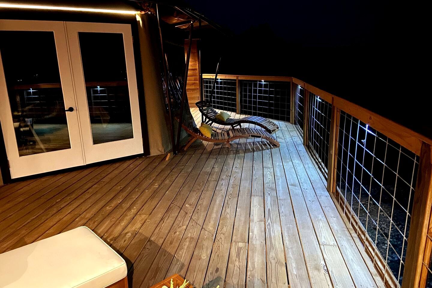 A wooden deck with a glass door, a cushioned chair, and a small table.