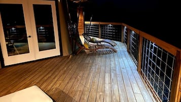 A wooden deck with a glass door, a cushioned chair, and a small table.