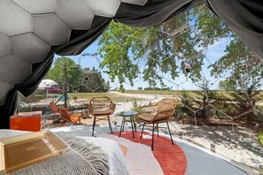 A tented outdoor area with two wicker chairs, a small table, and a red carpet.