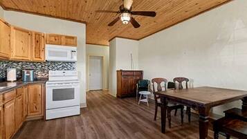 A kitchen with wooden cabinets, a microwave, an oven, and a dining area with a table and chairs.