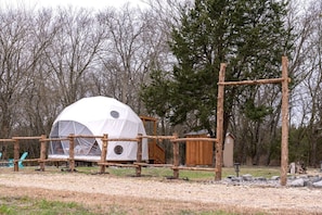 A dome-shaped tent with a wooden fence and a small wooden structure nearby.