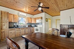 A kitchen with wooden cabinets, a dining table, and a ceiling fan.