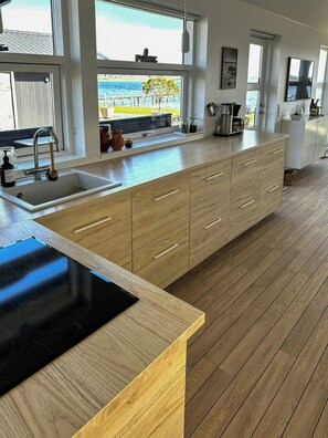 A modern kitchen with a large window, wooden cabinets, and a black countertop.