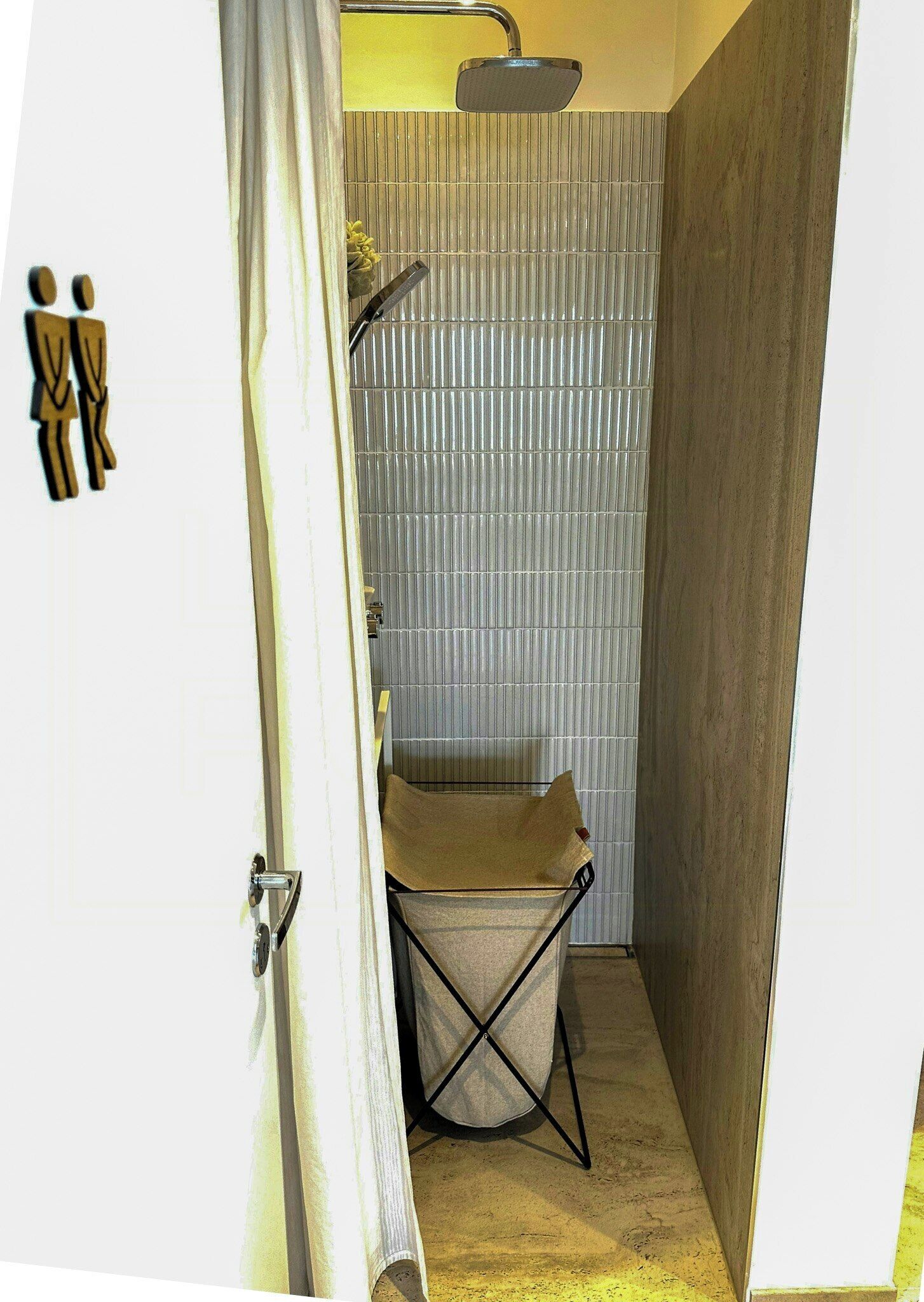 Une petite salle de bain avec une douche, un porte-serviettes et une porte avec un rideau.