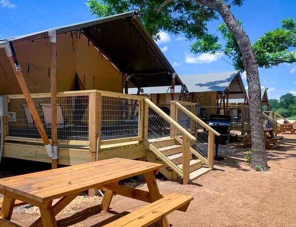 A wooden structure with a covered area, a fenced-in space, and a picnic table.