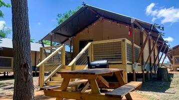 A wooden cabin with a covered porch, a picnic table, and a grill.