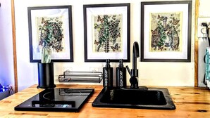 A kitchen with three framed botanical prints, a black countertop, and a coffee machine. - Sunshine Retreat- VCT#2 Glamping in Santa Ysabel, CA (Santa Ysabel)