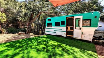 A mobile home with a door, windows, and a covered outdoor area.
