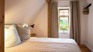 A bedroom with a bed, a window with curtains, a wooden ceiling, and a wall-mounted basket. - Idyllic country house between Hamburg and Berlin (Langen Jarchow)