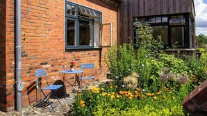 A brick building with a wooden extension, a garden with flowers, and outdoor seating. - Idyllic country house between Hamburg and Berlin (Langen Jarchow)