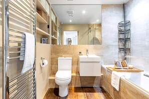 A modern bathroom with a toilet, sink, and shower area. - Design-led Flat Near Notting Hill (London)