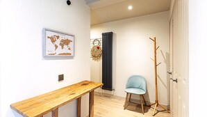 A room with a wooden table, a chair, a coat rack, a radiator, and a world map on the wall. - Design-led Flat Near Notting Hill (London)