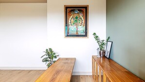 A room with a wooden bench, a small table, a cabinet with decorative items, and a framed picture on the wall. - Design-led Flat Near Notting Hill (London)