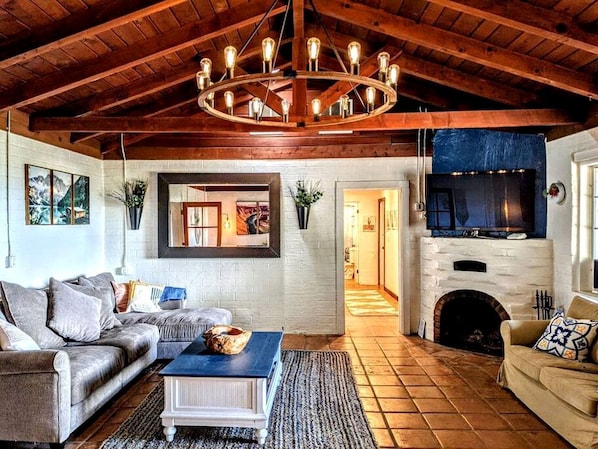 A living room with a fireplace, a sofa, a coffee table, and a chandelier.