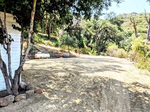 A dirt path leading to a white building with a tree in the foreground.