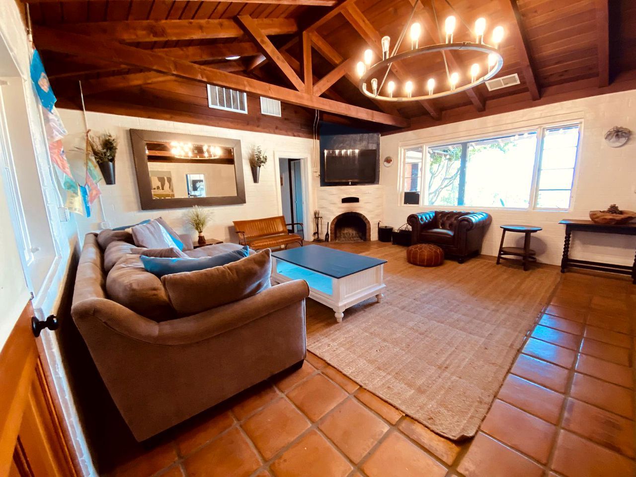 Un salón acogedor con un sofá marrón, una mesa de centro de cristal, una chimenea y un televisor montado en la pared.