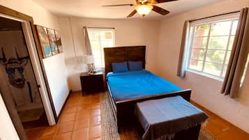 A bedroom with a bed, a ceiling fan, a window, and a door.