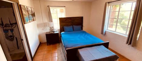 Un dormitorio con cama, ventilador de techo, ventana y puerta.