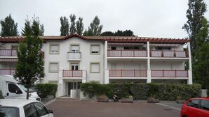 A multi-story residential building with balconies, a parking area, and a red car parked in front. - 🌿Cosy studio with 4 bedrooms and private terrace not overlooked 10min from beaches (Anglet)