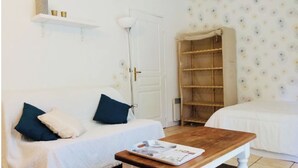 A room with a white sofa, a wooden table, a white door, and a wardrobe with a floral wallpaper. - 🌿Cosy studio with 4 bedrooms and private terrace not overlooked 10min from beaches (Anglet)