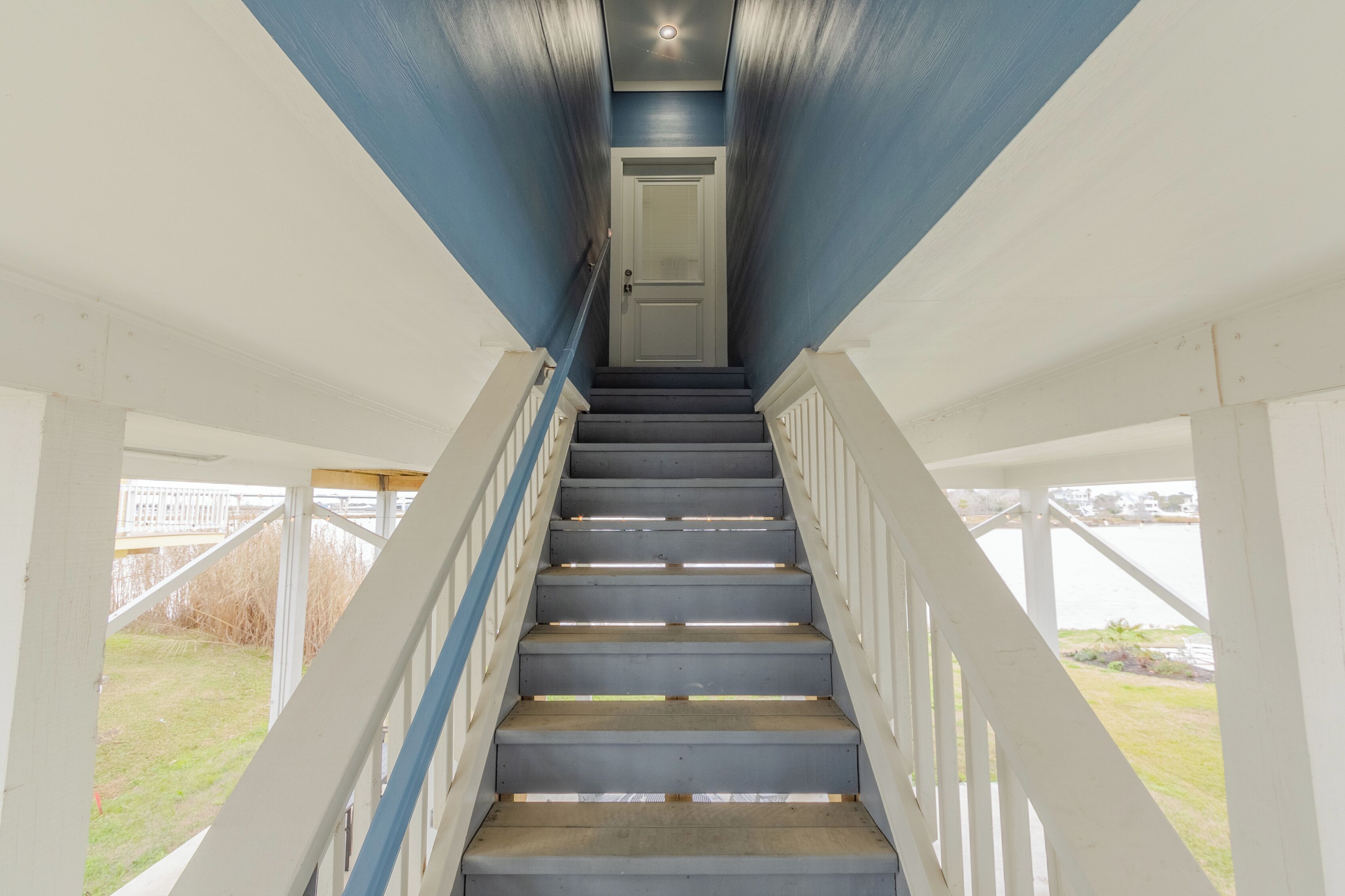 A staircase leading to a door with a view of a grassy area outside.