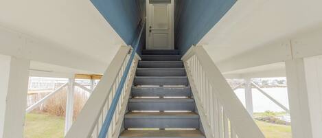 A staircase leading to a door with a view of a grassy area outside.