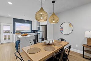 Eine moderne Küche mit einer großen Kochinsel, Edelstahlgeräten und einem Essbereich mit einem Holztisch und gewobenen Platzsets.