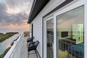 Ein Balkon mit Stühlen, einer Glastür und Blick auf ein Gewässer.
