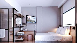 Habitación de hotel moderna con cama, armario, escritorio con tetera y un cuadro enmarcado en la pared.