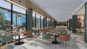 Un comedor moderno con mesas y sillas, ventanas amplias y vistas al exterior.