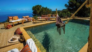 A poolside area with lounge chairs, a hammock, and a view of the sea. - Cottage with Aeolian Islands views near Cefalù (Cefalù)