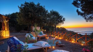 A patio with lounge chairs, a table, and string lights. - Cottage with Aeolian Islands views near Cefalù (Cefalù)
