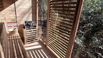 Een houten terras met uitzicht op een tuin, een houten bank en een houten tafel met een schaal.