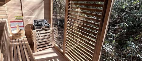 Una terraza de madera con vista a un jardín, un banco de madera y una mesa de madera con un cuenco.
