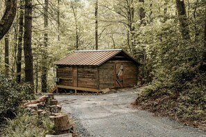 Una cabaña de madera rústica en un bosque, con un camino de grava que la conduce.